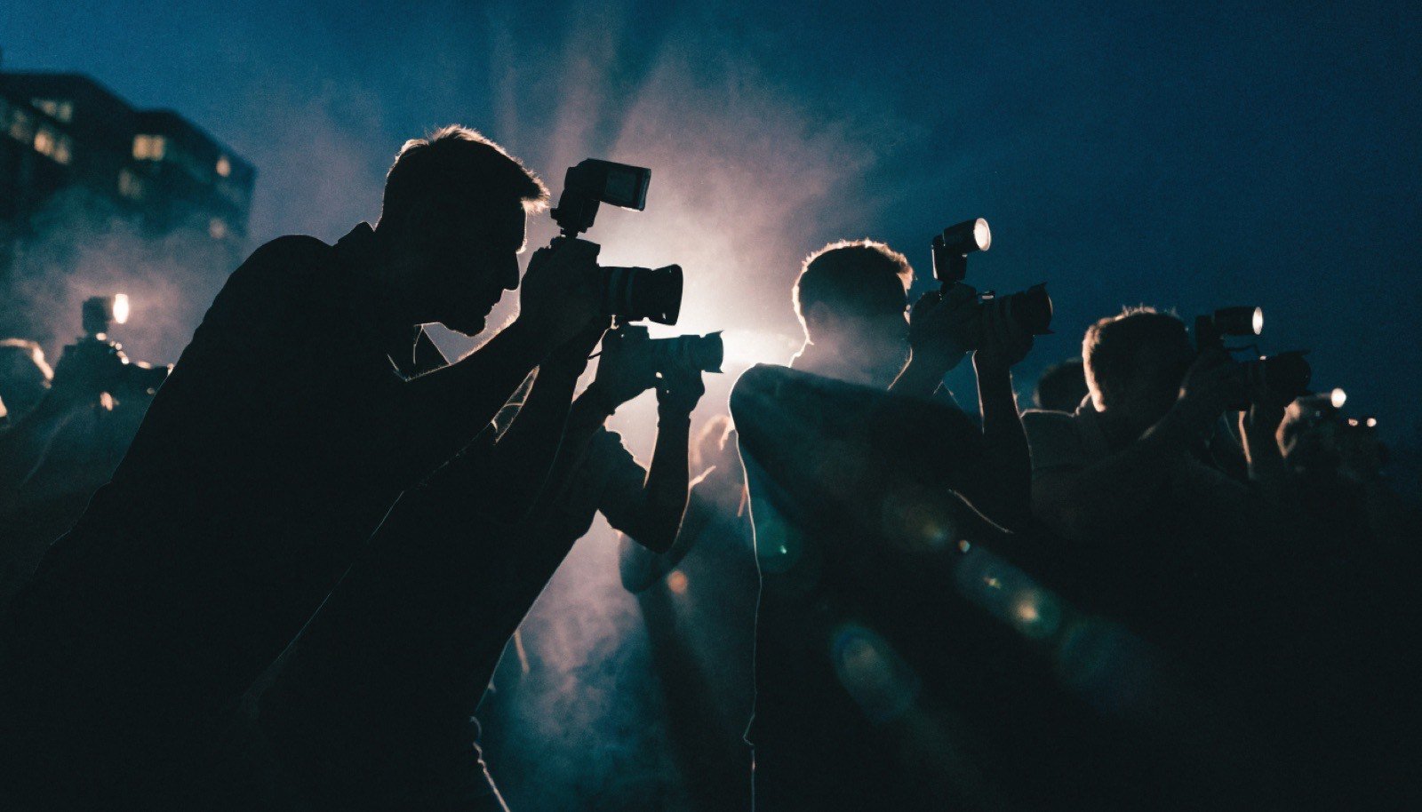Silhuetas de fotógrafos com câmeras em evento de famosos
