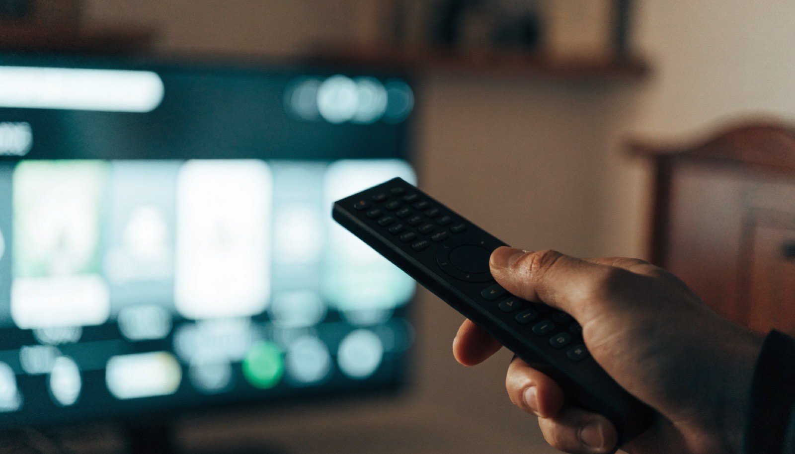 Tela de televisão com controle remoto em primeiro plano
