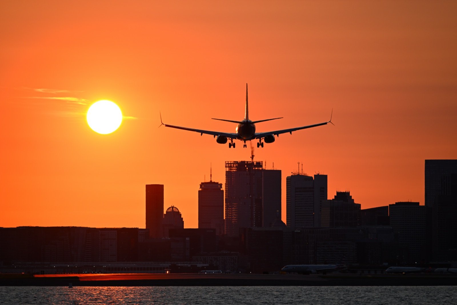Avião comercial pousando ao pôr do sol com skyline ao fundo