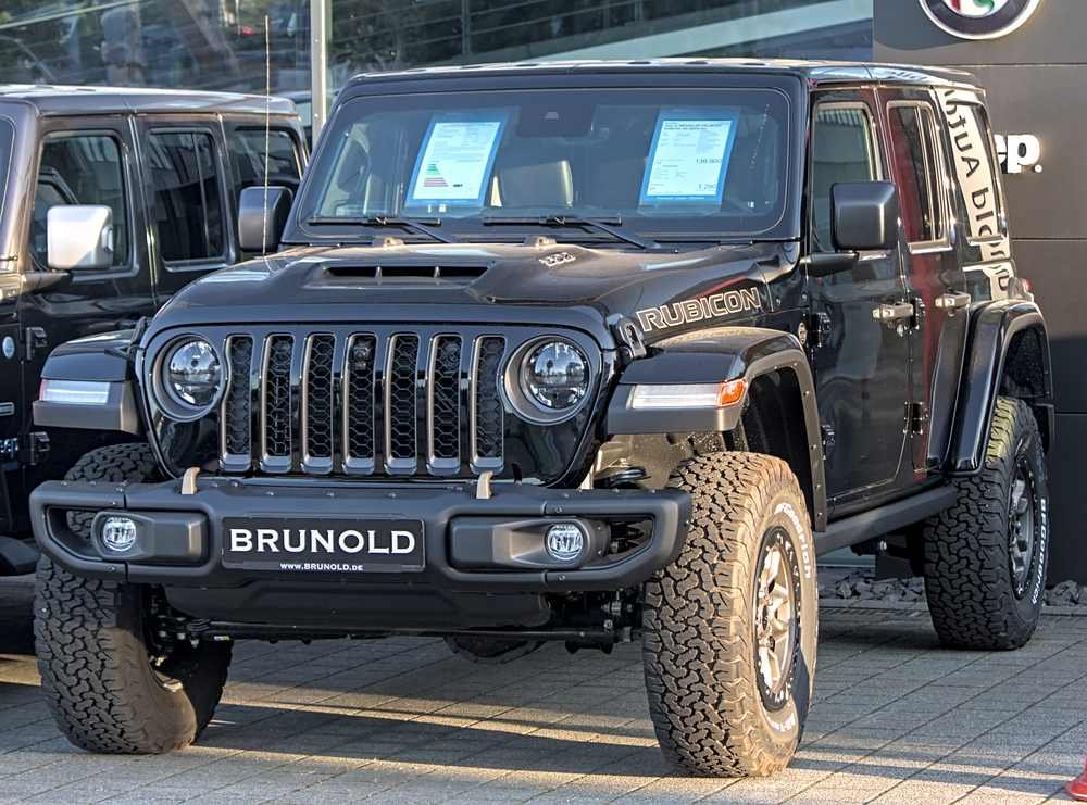 Jeep Wrangler Rubicon preto exposto em concessionária, com grade frontal característica e pneus off-road, sob luz natural de dia
