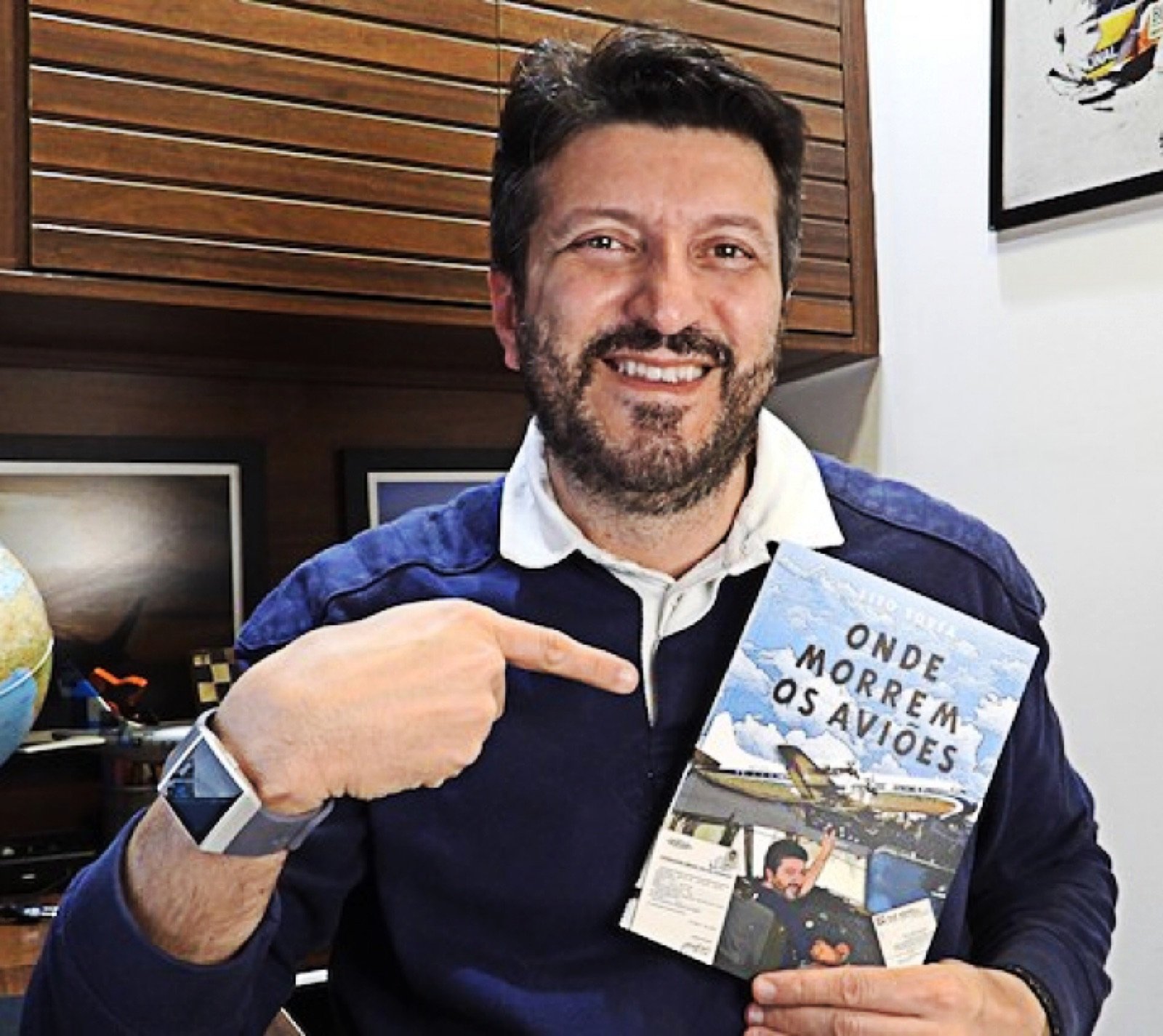 Lito Sousa sorridente segurando seu livro Onde Morrem os Aviões