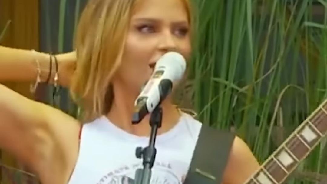A cantora Luísa Sonza tocando guitarra e cantando ao microfone
