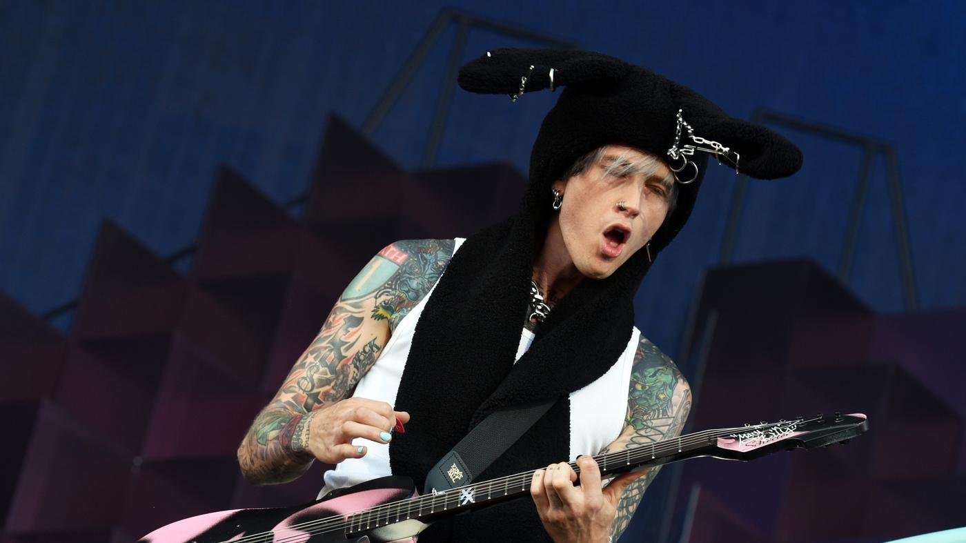 O rapper e guitarrista mgk, Machine Gun Kelly, tocando guitarra rosa em cima do palco