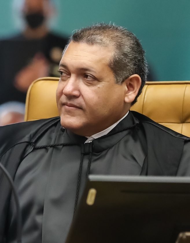 Kássio Nunes Marques, de becas pretas do STF, sentado em cadeira de couro amarela durante sessão do tribunal