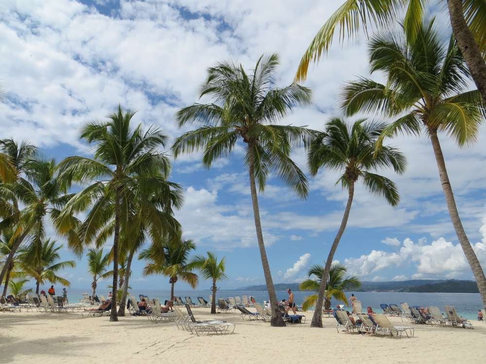 Praia tropical de areia branca com coqueiros e mar azul-turquesa na República Dominicana, país onde ocorreu o acidente com o ex-participante do Survivor Grécia
