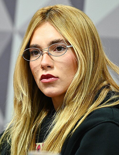 Virginia Fonseca em primeiro plano, cabelo loiro liso, durante evento oficial em Brasília